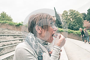 Traveling woman eating voraciously ice cream outdoors. Toned image, vintage style.