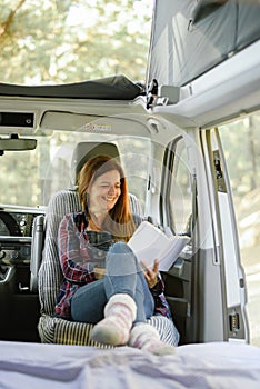 Traveling woman reading book in parked van