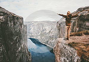 Traveling woman standing on cliff over fjord alone