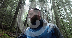 Traveling young tourist enjoying nature drinking hot tea while sitting in forest in rainy