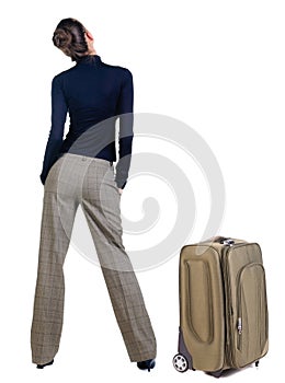 Traveling young woman with suitcas looking at wall.