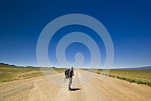 Traveller with backpack on a lonely road in desert