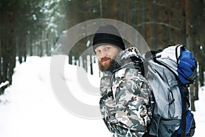 Traveller with backpack in winter forest