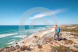 Traveller enjoys the view of the sandy beach of Praia do Malhao Sul on the Atlantic coast near Vila Nova de Milfontes, Odemira, photo