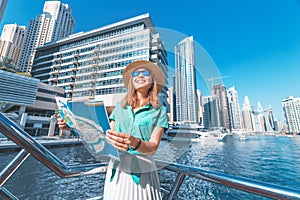 traveller girl with a map on a cruise ship at the Marina port in Dubai. Travel destinations and transport concept