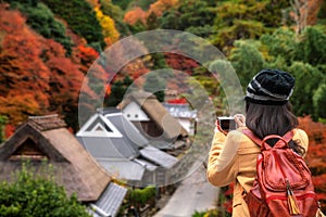 Traveller girl take a photo for the traditional japanese hut a autumn background