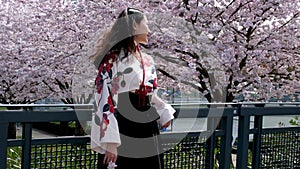 traveller girl walk beautiful young Oriental girl waving her head developing her hair against the background of cherry