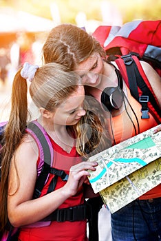 Traveller girls with backpack looking for way tourist paper map