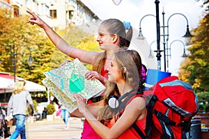 Traveller girls with backpack looking for way tourist paper map