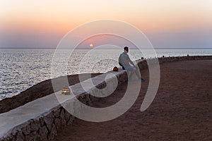 Traveller man with backpack on the beach over sunrise background