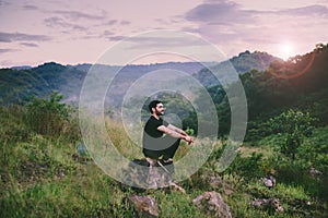 Traveller man with backpack sitting on rock at outdoor,Meditations to calm your mind and body photo