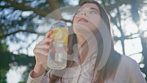 Traveller replenishing water summer park. Closeup female drinking lemon beverage