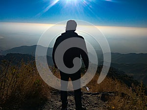 A traveller standing at cliff of a hill in Kasauli Himachal Pradesh India under clear sky sunlight landscape
