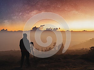 Traveller taking photograph of landscape sunrise and sky full of stars in dawn