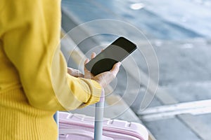 Traveller using smartphone application for booking taxi car service at airport.