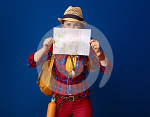 Traveller woman against blue background hiding behind map