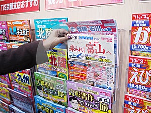 Traveller woman hand select and buy Japanese magazine at bookstore in Kyoto railway station, Japan