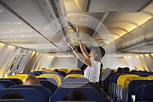 Traveller woman open overhead locker on airplane