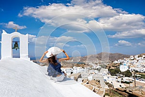 Traveller woman sits next to a orthodox, Greek church above the Chora of Ios