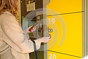 Traveller woman with smart phone opens or closes a numbered storage box in a public place. New business locker self