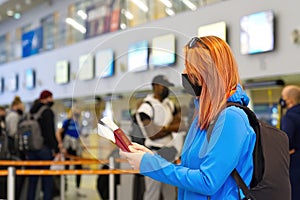traveller woman is wearing protective mask in International airport, travel under Covid-19 pandemic. Masked tourists at