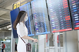 A traveller woman is wearing protective mask in International airport, travel under Covid-19 pandemic, safety travels, social