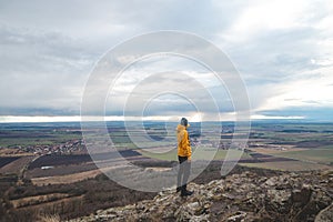 Traveller in a yellow jacket stands on top of Mount Rip and is pointing at the city of Prague. Exploring the Czech country