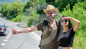 Travellers try to stop car. Couple hitchhikers travelling summer sunny day. Couple travelers man and girl hitchhiking at