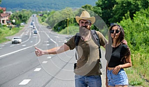 Travellers try to stop car. Hitchhiking is one of cheapest ways of traveling. Couple hitchhikers travelling summer sunny