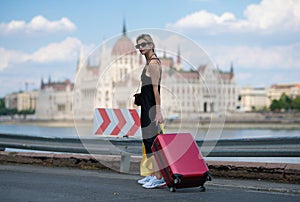 Travelling concept. Sexy young woman on trip walking with his luggage on street. Sensual girl with travel bag ready to