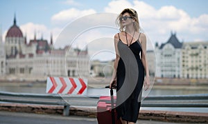 Travelling concept. Sexy young woman on trip walking with his luggage on street. Sensual girl with travel bag ready to