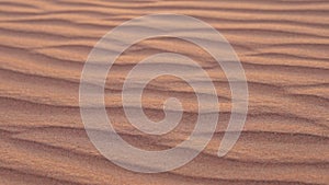 travelling in desert, closeup view of rippled sand in dune in sunset or sunrise, slow motion