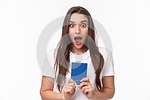 Travelling, holidays, summer concept. Close-up portrait of impressed, shocked young woman holding passport, drop jaw and