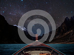 Travelling on lake at night by boat, sky full of star and milky way with mountains valley