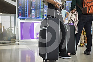 Travelling suitcase against flight information board on background. Concept of travel by airplane