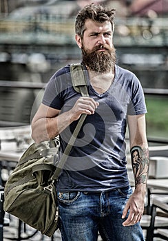 Travelling and vacations concept. Muscular man with beard and mustache carrying big sporty bag. Tourist explore city