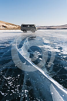 Travelling in winter at frozen lake Baikal in Siberia, Russia. Tourist van parking on ice with cracked line