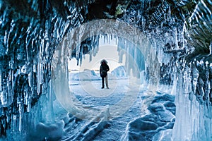 Travelling in winter, a man standing on Frozen lake Baikal with Ice cave in Irkutsk Siberia, Russia