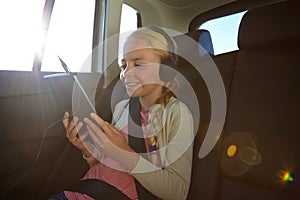 Travels are more fun with your tablet. a little girl traveling in a car.