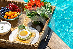 Tray with assorted breakfast meal and drinks near swimming pool