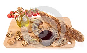 Tray with baguette, nuts, olives, oil, vine, tomatoes on white.