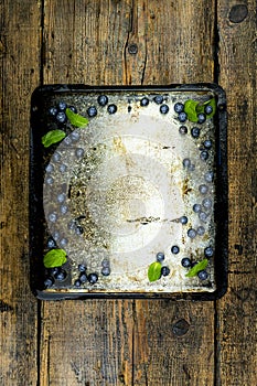 Tray with blueberries,beads and mint leaves with emty space in the middle on a rustic wooden table