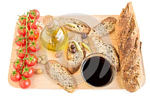 Tray with bread, olives, olive oil, vine, tomatoes on white.