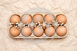 A tray of brown fresh hen`s eggs on wrinkled kraft paper. Eco-friendly egg production photo
