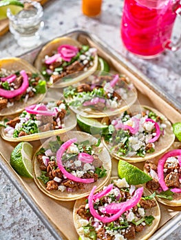Tray of carne asada tacos topped with pickled onions and cojita cheese