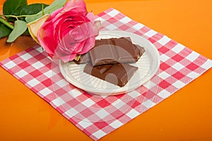 A tray with chocolate and a pink rose