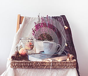 A tray with a cup of coffee, apples in a jar, light chain, flowers and a scarf