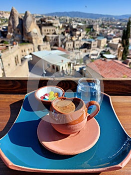 The tray with a cup of coffee, a glass of water, and sweets against the Goreme Open Air Museum