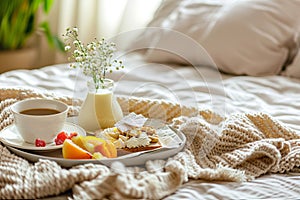 Tray with a cup of coffee, pastries, and fresh milk on a bed with white linens and small white flowers