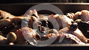 Tray filled with chicken breasts inside oven. Action. Close up of chicken being baked in the oven with olives, spices